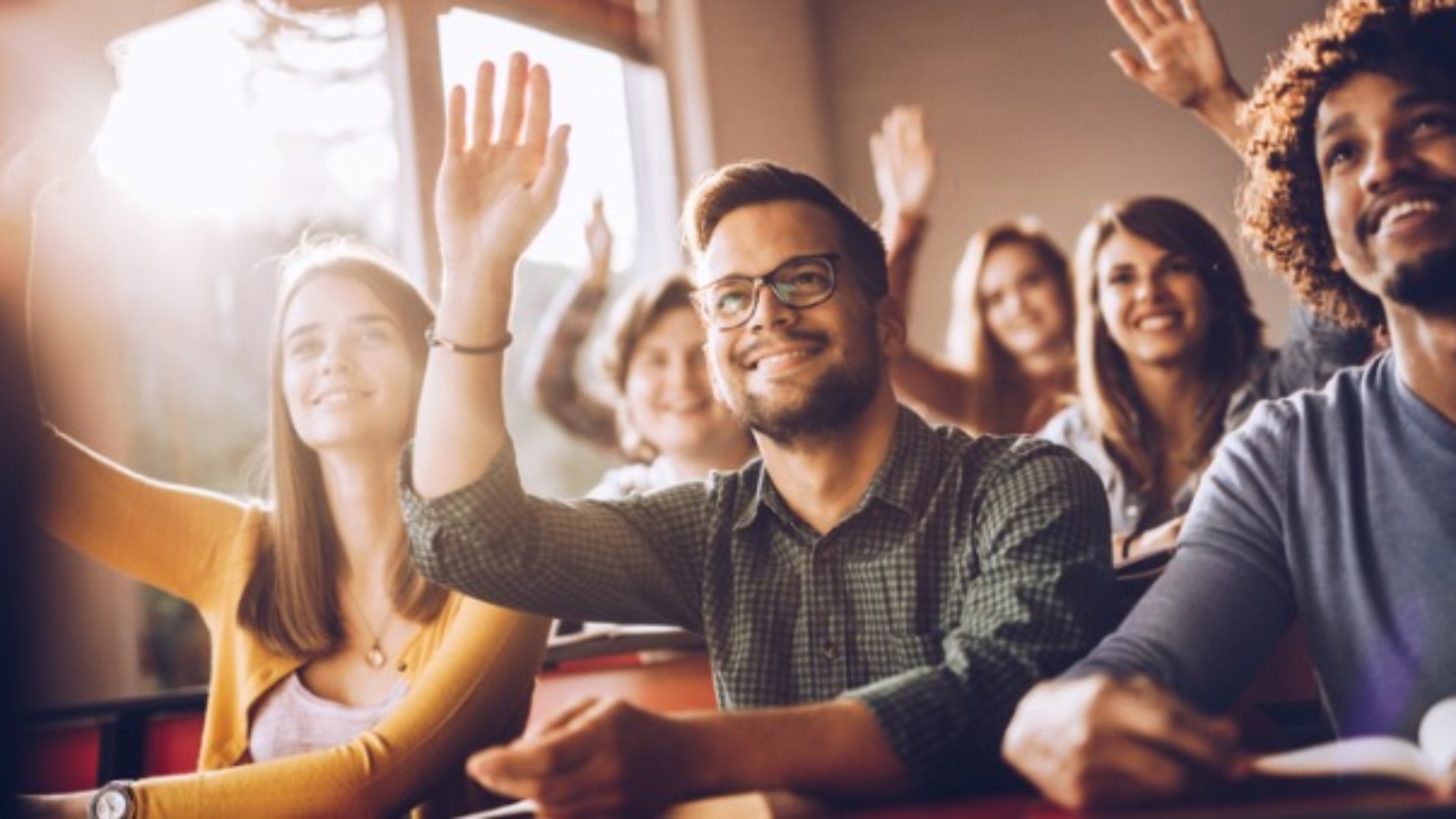 happy-students-raising-their-hands-on-a-class-at-lecture-hall-picture-id1163474547